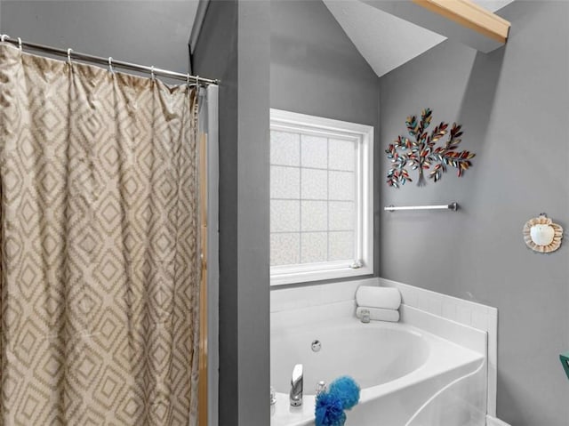 bathroom with a tub to relax in and vaulted ceiling