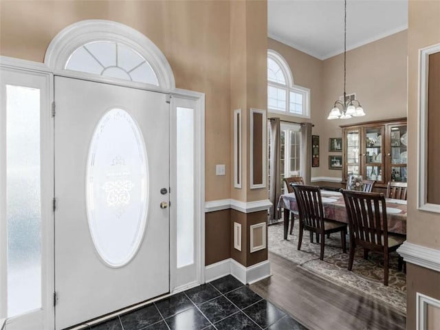 tiled foyer with a high ceiling, crown molding, and a chandelier