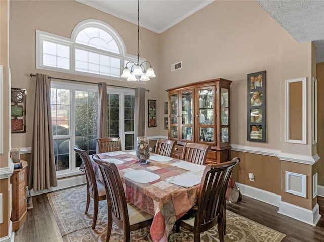 dining area with a high ceiling, dark hardwood / wood-style floors, and an inviting chandelier