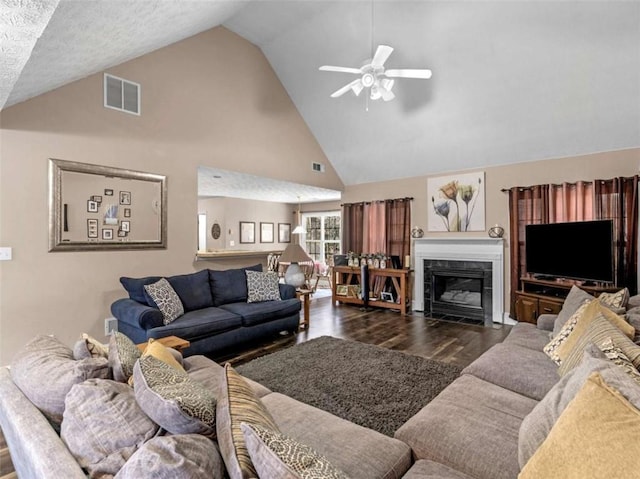 living room featuring ceiling fan, high vaulted ceiling, dark hardwood / wood-style floors, a high end fireplace, and a textured ceiling