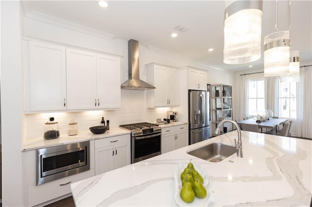 kitchen with decorative backsplash, wall chimney exhaust hood, appliances with stainless steel finishes, light stone counters, and sink