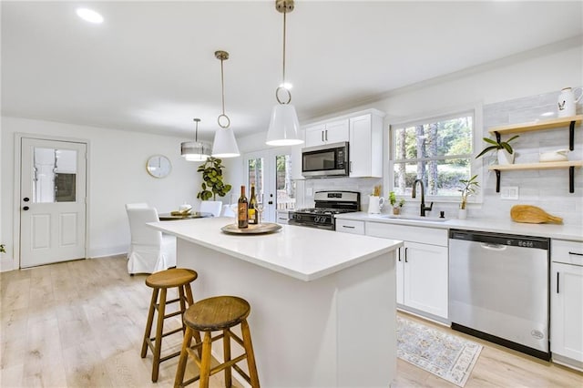 kitchen with stainless steel appliances, white cabinetry, sink, and pendant lighting