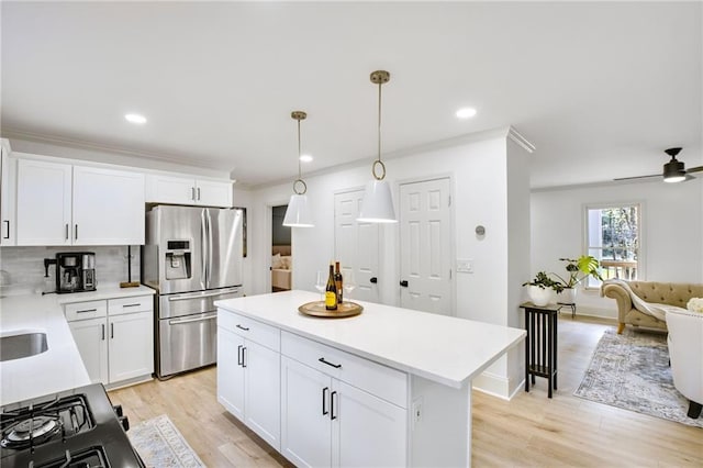 kitchen featuring white cabinets, light hardwood / wood-style flooring, pendant lighting, and stainless steel fridge