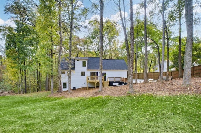 rear view of house featuring a wooden deck and a lawn