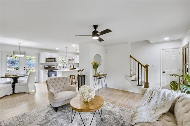 living room with ornamental molding, light hardwood / wood-style flooring, and ceiling fan