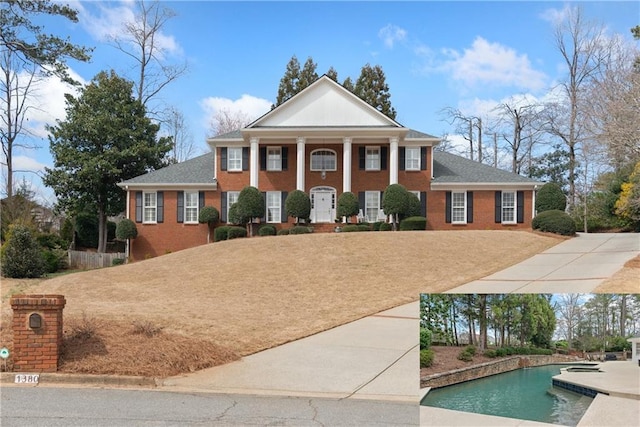 greek revival house featuring brick siding and an outdoor pool