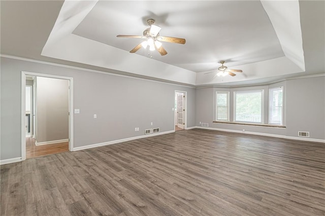 empty room with ceiling fan, wood-type flooring, a tray ceiling, and ornamental molding