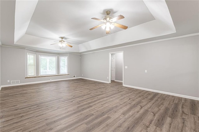 spare room with hardwood / wood-style floors, ceiling fan, and a raised ceiling