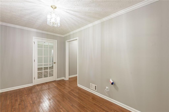 empty room with crown molding, hardwood / wood-style flooring, a textured ceiling, and an inviting chandelier