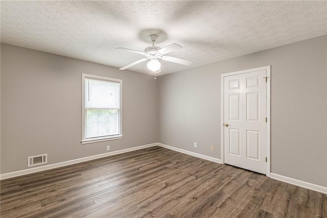 empty room with dark hardwood / wood-style floors, a textured ceiling, and ceiling fan