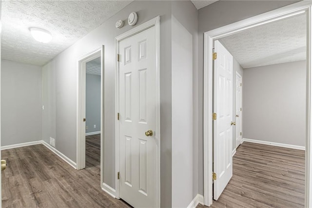 corridor with hardwood / wood-style floors and a textured ceiling