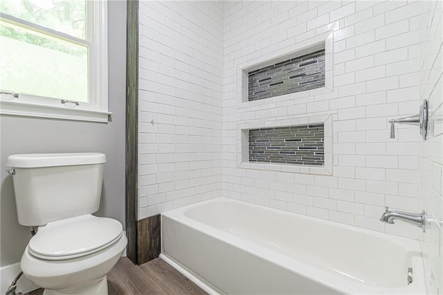 bathroom with tiled shower / bath, hardwood / wood-style flooring, and toilet