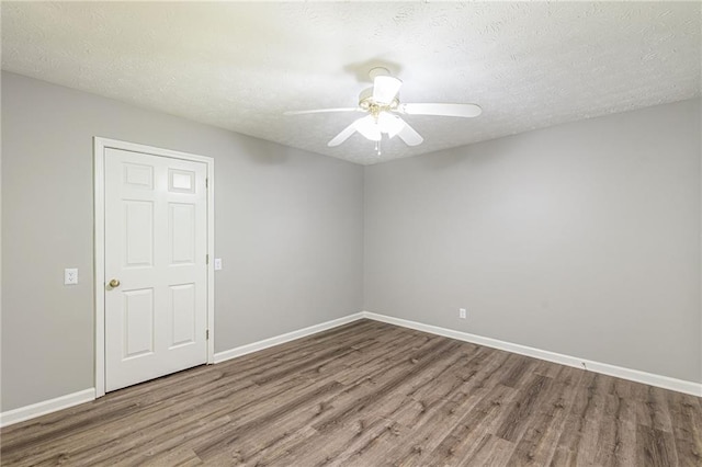 empty room featuring ceiling fan, wood-type flooring, and a textured ceiling