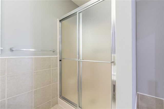 bathroom with a shower with door and tile walls