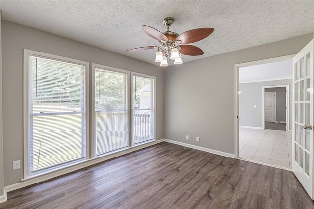 spare room featuring a textured ceiling, wood-type flooring, french doors, and ceiling fan