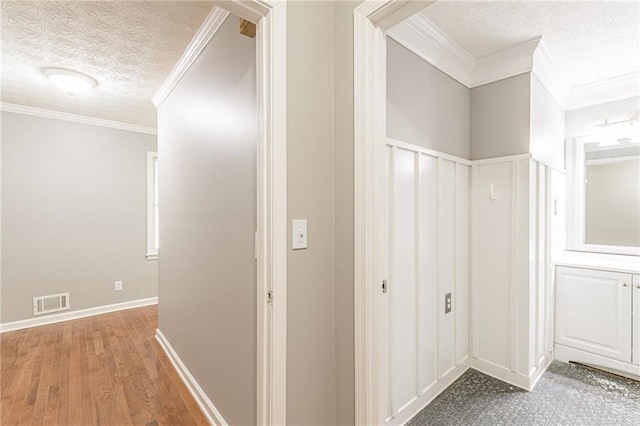 hall with crown molding, a textured ceiling, and hardwood / wood-style flooring