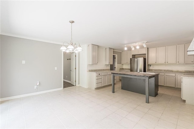 kitchen with a center island, a kitchen bar, pendant lighting, rail lighting, and stainless steel refrigerator