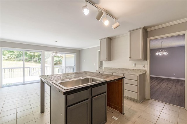 kitchen featuring hanging light fixtures, sink, crown molding, gray cabinets, and a chandelier