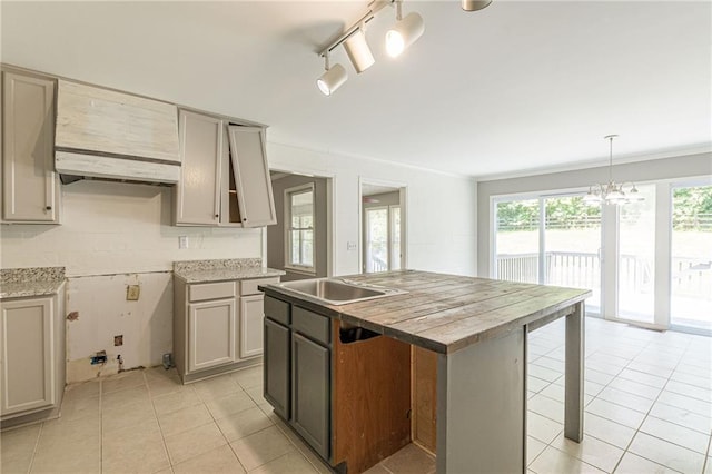 kitchen with gray cabinetry, light tile patterned floors, a center island, and pendant lighting