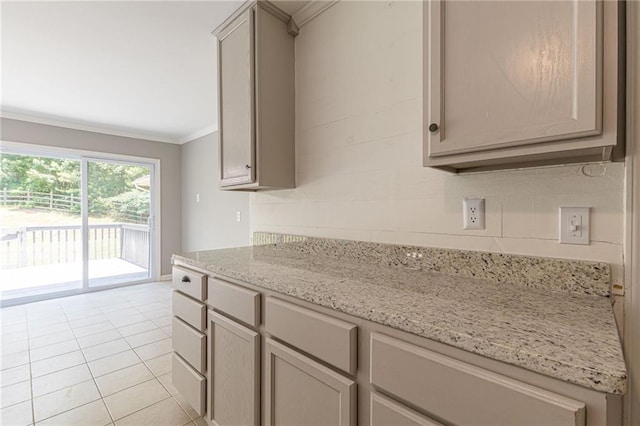 kitchen featuring light stone countertops, ornamental molding, light tile patterned floors, and gray cabinets