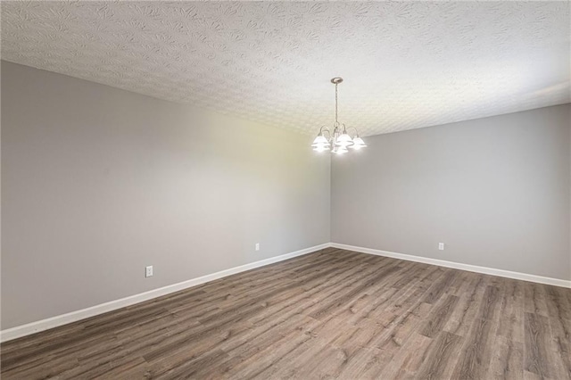 unfurnished room featuring a notable chandelier, a textured ceiling, and hardwood / wood-style floors