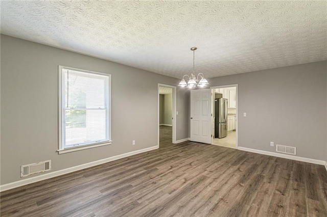 spare room featuring wood-type flooring, a textured ceiling, and a chandelier