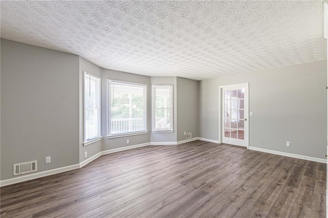 empty room featuring dark hardwood / wood-style floors and a textured ceiling