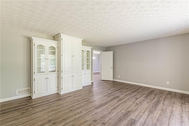 empty room featuring a textured ceiling and wood-type flooring