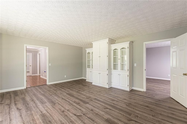 spare room with a textured ceiling and dark hardwood / wood-style flooring