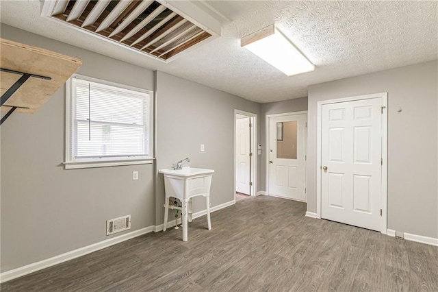 unfurnished room with dark wood-type flooring and a textured ceiling