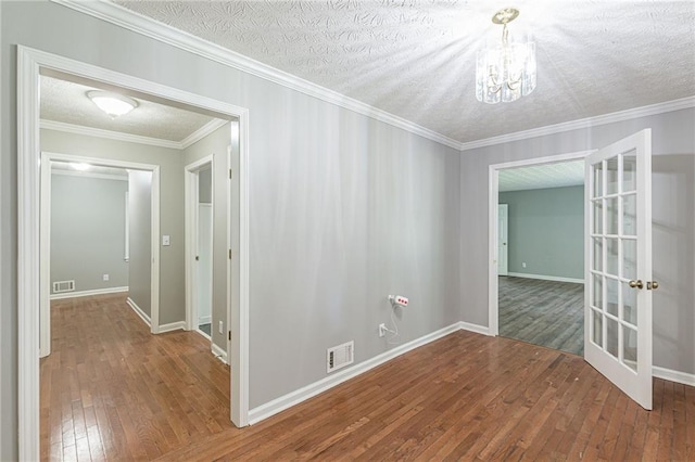 unfurnished room featuring a notable chandelier, a textured ceiling, and hardwood / wood-style floors