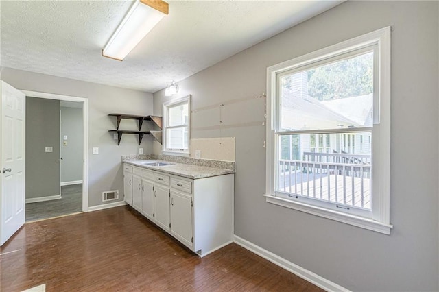 kitchen featuring white cabinetry, a textured ceiling, a healthy amount of sunlight, and dark hardwood / wood-style flooring