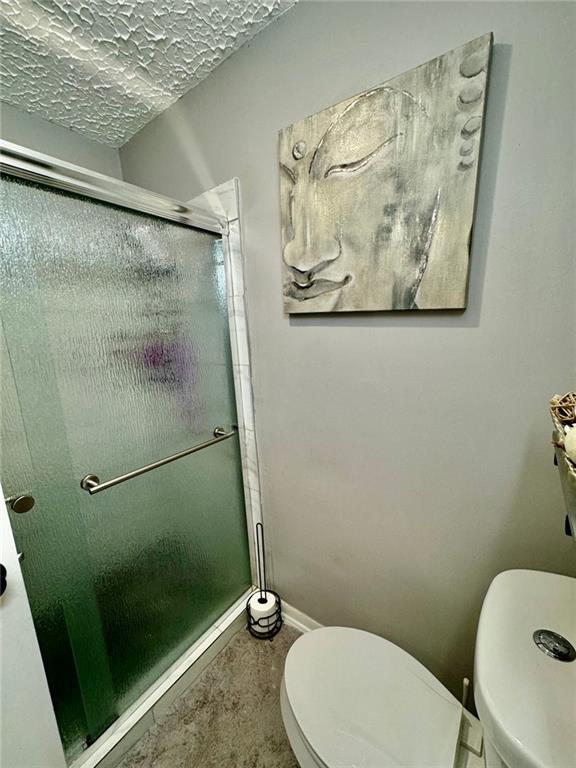 312 E Broad St, Winder, GA 30680 - bathroom featuring toilet, a shower stall, and baseboards