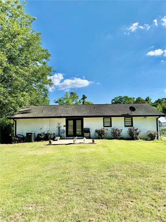 312 E Broad St, Winder, GA 30680 - back of property featuring brick siding, a yard, a patio area, and central air condition unit