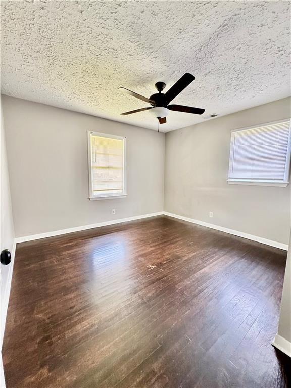 312 E Broad St, Winder, GA 30680 - spare room with ceiling fan, dark wood-style flooring, a textured ceiling, and baseboards