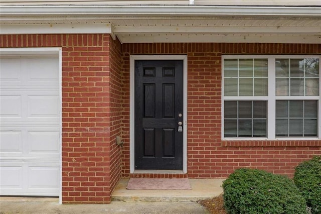 entrance to property with a garage and brick siding