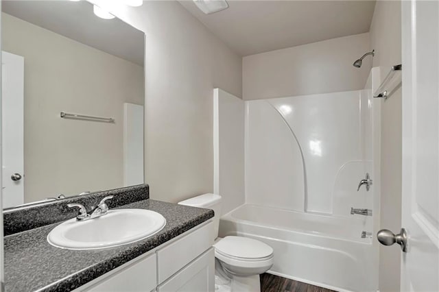 full bathroom with wood-type flooring, vanity, washtub / shower combination, and toilet