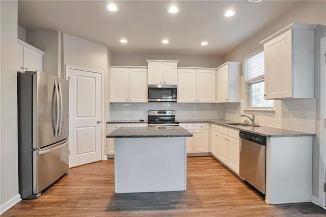 kitchen with stainless steel appliances, a kitchen island, sink, and white cabinets