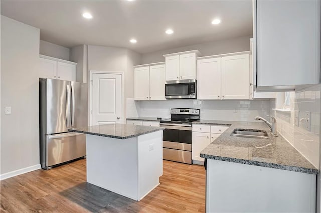 kitchen with white cabinetry, stainless steel appliances, sink, and a kitchen island