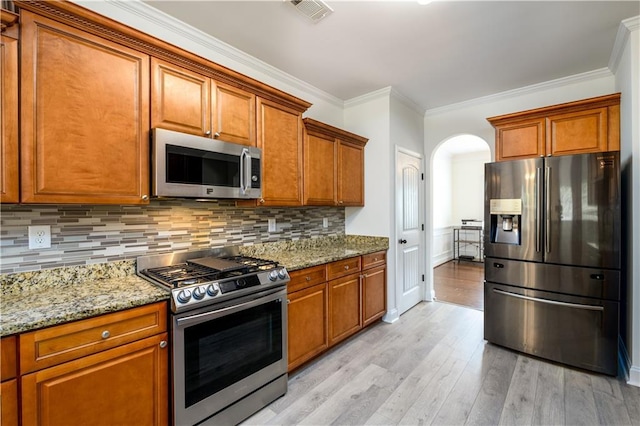 1076 Scenic Park Trl, Lawrenceville, GA 30046 - kitchen with stainless steel appliances, crown molding, brown cabinetry, light wood finished floors, and light stone counters