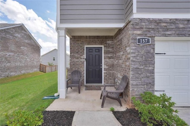 doorway to property featuring stone siding, brick siding, a lawn, and fence