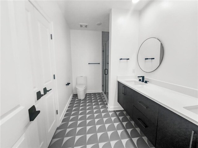 bathroom featuring tile patterned flooring, a shower with shower door, dual vanity, and toilet