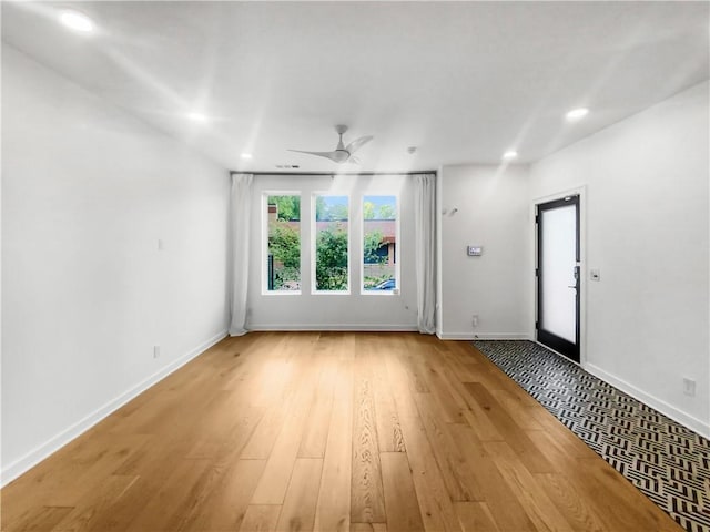 empty room with ceiling fan and light hardwood / wood-style flooring