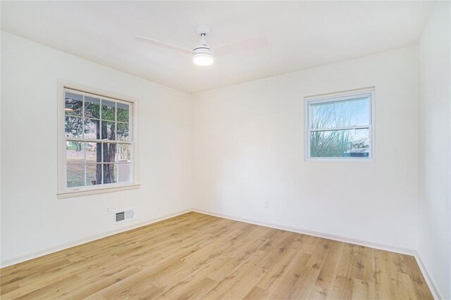 empty room featuring ceiling fan, light wood-type flooring, and a wealth of natural light