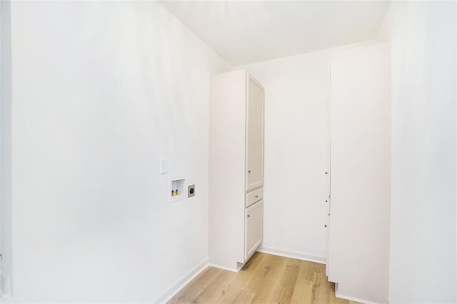 laundry room featuring washer hookup, light hardwood / wood-style floors, and cabinets