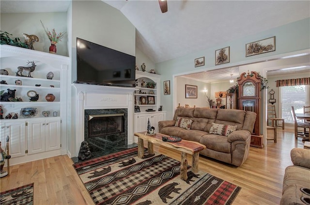living room featuring a premium fireplace, light hardwood / wood-style flooring, ceiling fan, and lofted ceiling