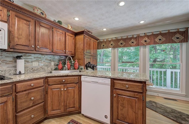 kitchen featuring a textured ceiling, sink, light hardwood / wood-style floors, and white appliances