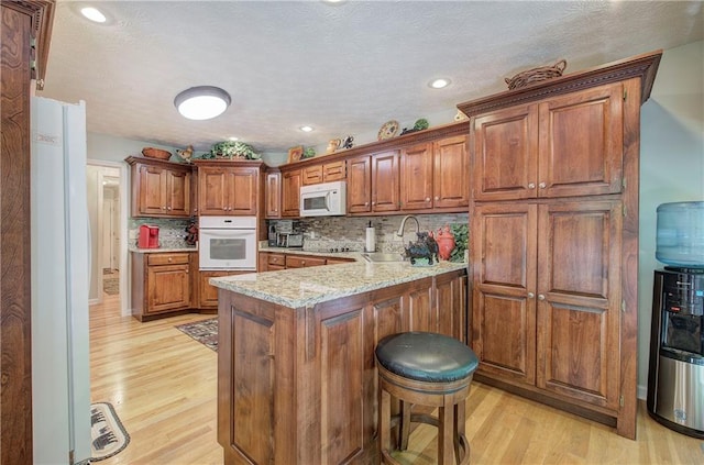 kitchen featuring kitchen peninsula, sink, white appliances, and light hardwood / wood-style flooring