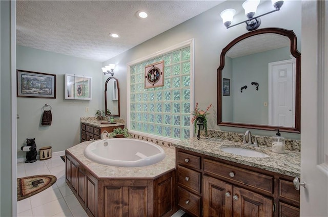 bathroom with a tub to relax in, tile patterned flooring, vanity, and a textured ceiling
