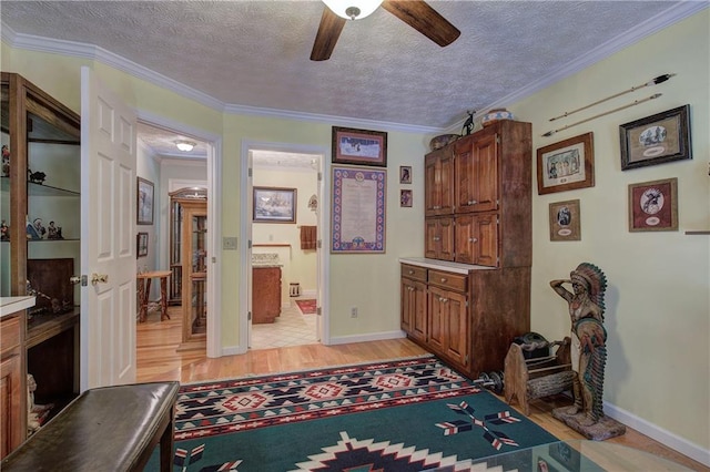 interior space with a textured ceiling, light hardwood / wood-style flooring, ceiling fan, and crown molding